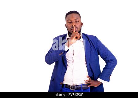Porträt eines hübschen jungen Geschäftsmannes, der einen eleganten Anzug trägt und mit dem Finger über dem Mund ein Zeichen der Stille macht. Stockfoto