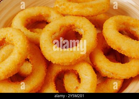 Knusprige, goldene Zwiebelringe liegen in einem rustikalen Korb, deren knusprige Textur einen geschmackvollen Biss verspricht Stockfoto