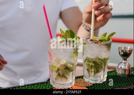 Erfrischende Mojito-Cocktails, die an einem sonnigen Tag am Ufer des Wassers serviert werden. Stockfoto