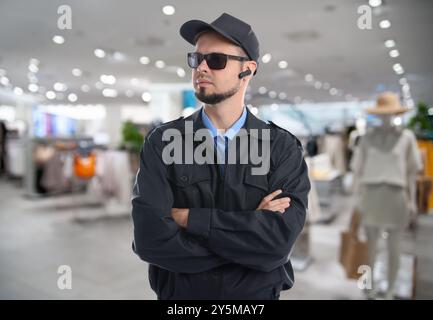 Sicherer Sicherheitsschutz mit Ohrhörer im Bekleidungsgeschäft Stockfoto