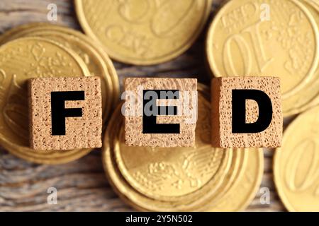 Würfel mit den Buchstaben Fed (Federal Reserve System) und Münzen auf Holztisch, flach gelegt Stockfoto