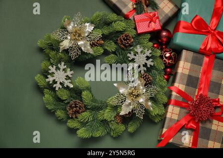 Weihnachtskranz mit Kegeln, Kugeln, dekorativen Schneeflocken und Geschenkboxen auf grünem Hintergrund, flach gelegt Stockfoto