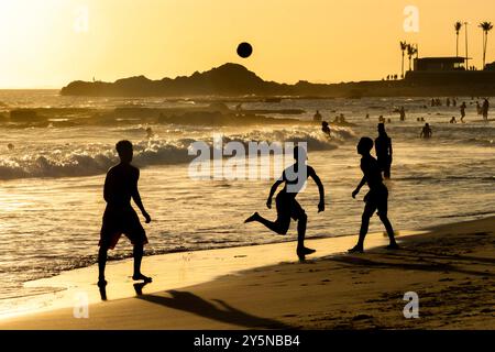 Salvador, Bahia, Brasilien - 6. Dezember 2019: Menschen werden bei Sonnenuntergang am Strand von Farol da Barra in Salvador, Bahia, beim Fußballspielen beobachtet. Stockfoto