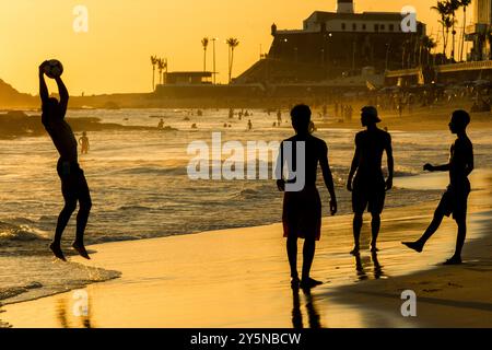 Salvador, Bahia, Brasilien - 6. Dezember 2019: Menschen werden bei Sonnenuntergang am Strand von Farol da Barra in Salvador, Bahia, beim Fußballspielen beobachtet. Stockfoto