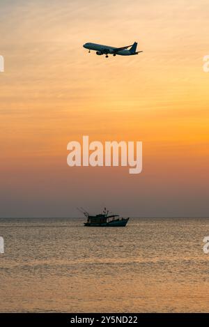Passagierflugzeug landet über dem Meer und ein schwimmendes Fischereischiff Stockfoto
