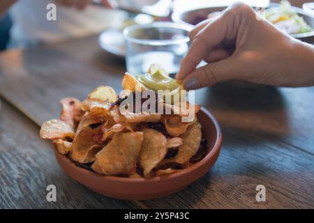Unerkennbare kaukasierin, die Chips aus einer Schüssel pflückt Stockfoto