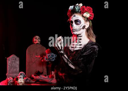 Frau mit Leichnam-Make-up, Horrorkostüm und Blumenhaarband, um dios de los muertos an Halloween zu feiern. Eine furchterregende Dame, gekleidet als La Catrina Charakter am Tag der Toten fiesta Stockfoto