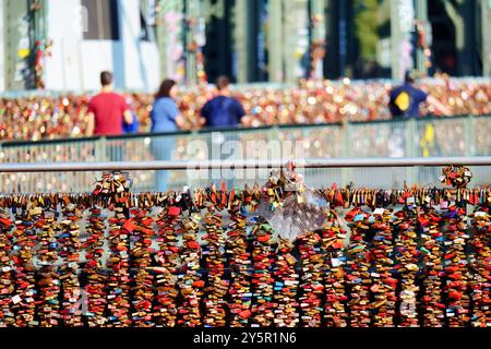 Tausende von Liebesschlössern auf dem Geländer der hohenzollernbrücke in der kölner Altstadt mit Touristen und Zug im verschwommenen Hintergrund Stockfoto