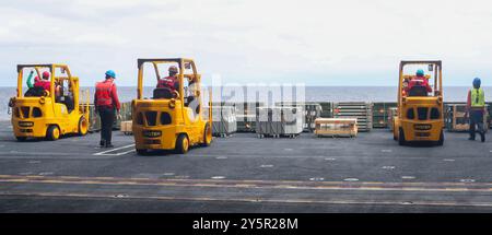 Seeleute, die der Waffenabteilung zugewiesen sind, bereiten sich darauf vor, Geschütze in der Hangarbucht an Bord des Flugzeugträgers USS George Washington (CVN 73) der Nimitz-Klasse zu bewegen, während sie am 20. September 2024 im Pazifischen Ozean unterwegs sind. Als integraler Bestandteil der U.S. Pacific Fleet betreibt die U.S. 3rd Fleet Marinestreitkräfte im Indo-Pazifik und bietet zudem realistische und relevante Schulungen an, die notwendig sind, um die zeitlosen Aufgaben unserer Navy in der Seestreitkontrolle und der Kraftprojektion einwandfrei auszuführen. US 3rd FLE Stockfoto