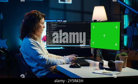 Entwickler, der Software-Debugging auf dem Green-Screen-PC zu Hause durchführt und Codezeilen auf Monitoren überprüft. IT-Profi im Wohnzimmer, die Codierungsprobleme auf Modellcomputer, Kamera A beheben Stockfoto