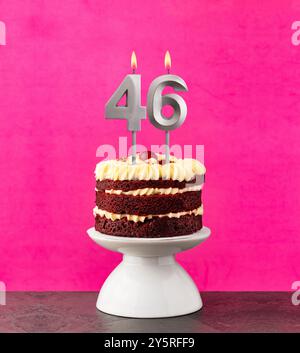 Roter Samtkuchen - Geburtstagsnummer 46 auf rosafarbenem Hintergrund. Stockfoto