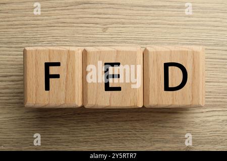 Würfel mit den Buchstaben Fed (Federal Reserve System) auf Holztisch, Draufsicht Stockfoto