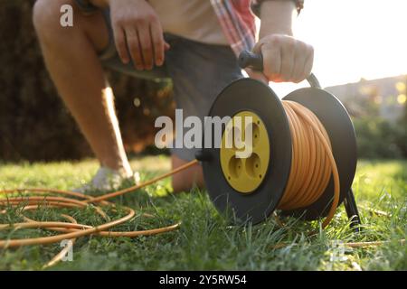 Mann mit Verlängerungskabel auf grünem Gras draußen, Nahaufnahme Stockfoto