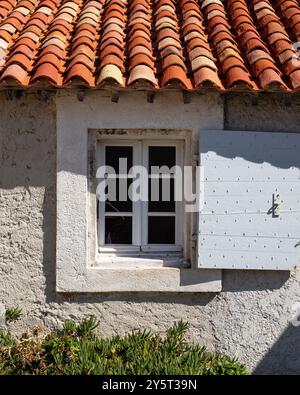 Mediterranes Cottage mit Fenster, Rollladen und spanischen Fliesen in der Mittagssonne. Stockfoto