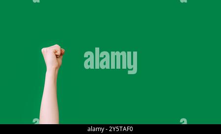 Klopfende Hand. Protestarm. Anspruchsvolle Geste. Weibliche erhobene geballte Faust, die isoliert auf grünem Leerraumhintergrund schlägt. Stockfoto