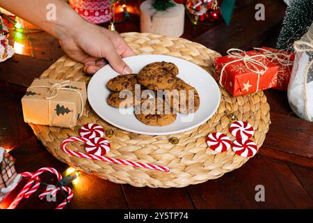 Männliche Hand, die weihnachtskekse auf Holztisch mit weihnachtsdekoration platziert, weihnachtsessen-Konzept Stockfoto