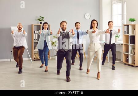 Yogi-Büromitarbeiter stehen in Yoga-Pose, Mitarbeitergruppe in formeller Kleidung, die Übungen macht Stockfoto