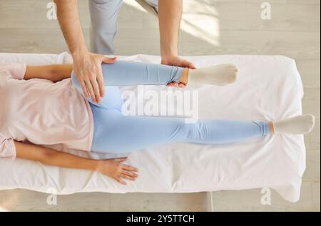 Chiropraktiker oder Physiotherapeutin, die das Knie einer Patientin auf einem medizinischen Bett in der Klinik beugt Stockfoto