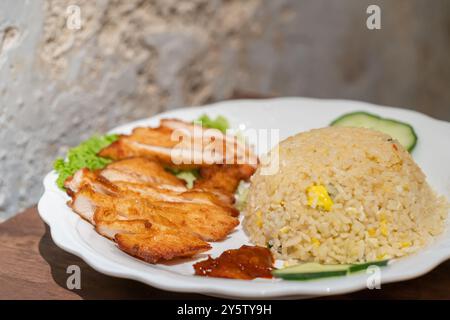 Nahaufnahme des frittierten Reis mit Hähnchenkotelett, Gurke, Salat Korallen und Chilisauce. Stockfoto
