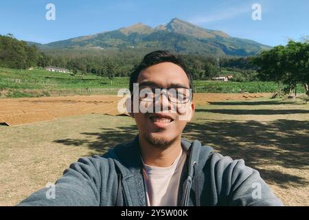 Asiatischer Mann, der im Urlaub Selfie mit Berghintergrund macht Stockfoto