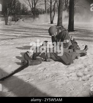 Amerika der 1940er Jahre Vintage-Foto einer Demonstration vor Armeeärzten und Offiziersanwärtern an der US Army Field Service School. Drei Kompaniehelfer (d.h. unbewaffnete medizinische Soldaten) sind an jede Infanteriekompanie sowie an andere Kampfeinheiten gebunden und ziehen mit ihnen in die Tiefe der Schlacht. Wenn ein Verwundeter fällt, leistet er erste Hilfe und bringt ein Schild auf sein Bajonett, das die Müllträger finden können. Carlisle, Pennsylvania. Februar 1943 Stockfoto