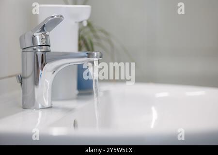 Ein Wasserhahn mit fließendem Wasser. Wasserhahn aus Chrommaterial. Stockfoto