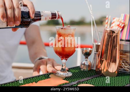 Erfrischender Sommercocktail, der über Eis mit lebhaften Farben und Bokeh-Hintergrund gegossen wird. Stockfoto