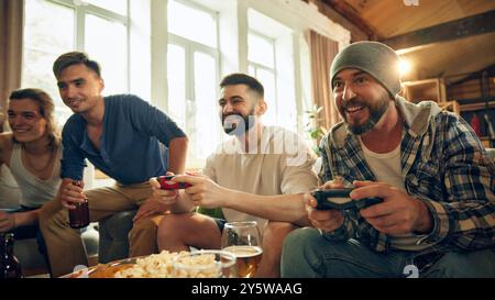 Jeder ist in Aktion, aber zwischen ernsten Momenten ist viel Lachen. Popcorn, Drinks und Spiel vereinen sie für einen Nachmittag voller Spaß. Stockfoto