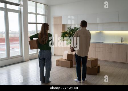Einweihungen für junge Familien. Zusammen mit Kartonkisten stehen Sie nach dem Umzug in einem neuen Haus zusammen Stockfoto