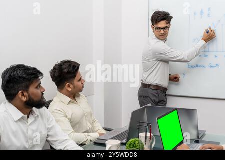 Dieses fesselnde Stockfoto zeigt einen indischen Profi, der aktiv an einer Schulung in einem modernen Büroumfeld teilnimmt. Das Bild sh Stockfoto