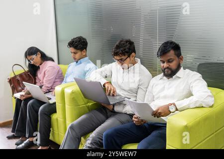 Berufsbewerber, vielfältig und sehr erfahren, sitzen in einem modernen Wartezimmer, bereiten sich auf ihre Vorstellungsgespräche vor, konkurrieren Stockfoto