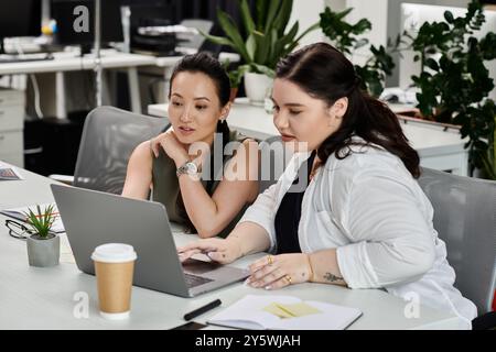 Zwei Fachleute führen ein fokussiertes Gespräch, während sie Dokumente auf einem Notebook prüfen. Stockfoto