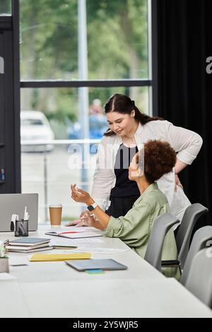 Zwei elegante Geschäftsfrauen führen an ihrem Arbeitsplatz ein durchdachtes Gespräch. Stockfoto