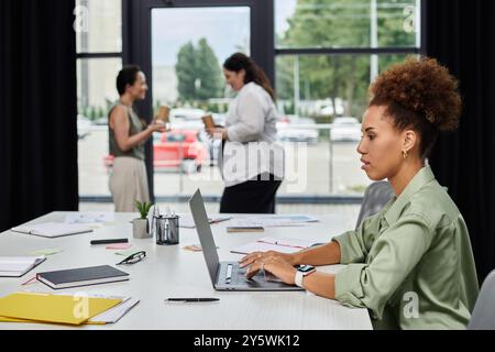 In einem modernen Büro unterhalten sich zwei Profis, während ein anderer fleißig arbeitet. Stockfoto