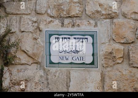 Ein Straßenschild mit Keramikfliesen auf einer alten Steinmauer in Hebräisch, Arabisch und Englisch, das den Eingang durch das neue Tor zur Altstadt von Jerusalem markiert. Stockfoto