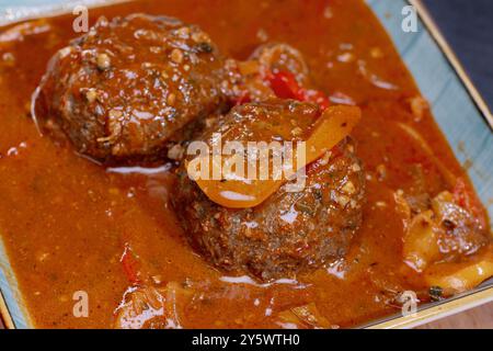 Nahaufnahme mit köstlichen Fleischbällchen in einer reichhaltigen Tomatensauce mit Paprika und Gewürzen. Stockfoto