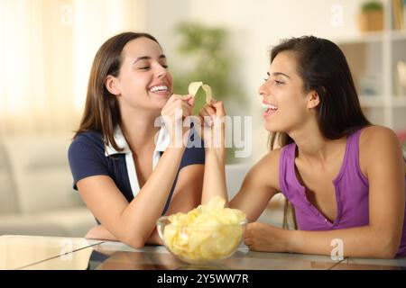 Glückliche Freunde, die zu Hause mit Kartoffelchips toasten Stockfoto