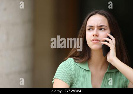 Die verdächtige Frau spricht am Telefon und sitzt auf der Straße Stockfoto