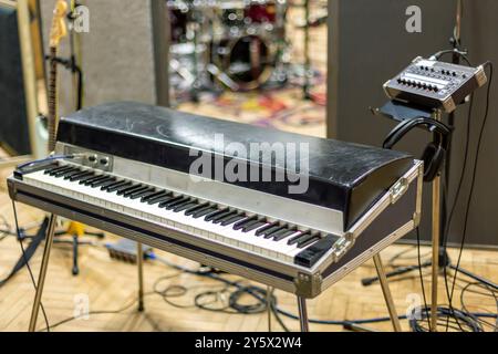 E-Piano- und Synthesizer-Setup in einem Musikstudio mit Mikrofonständern und Schlagzeug im Hintergrund. Stockfoto