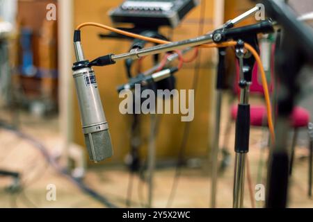 Studiomikrofon mit Pop-Filter vor verschwommenem Hintergrund von Musikgeräten. Stockfoto