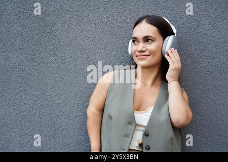 Eine fröhliche brünette Frau mit einem fröhlichen Lächeln lauscht draußen Musik, während sie sich im warmen Sonnenlicht sonnt. Stockfoto