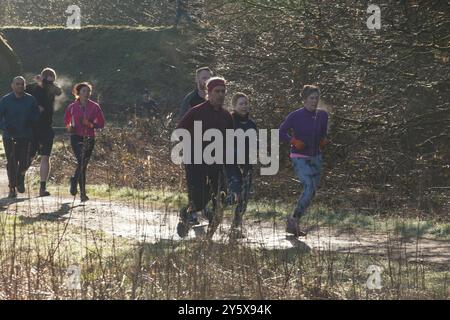 Gruppe von Menschen, die einen morgendlichen Jog auf einem sonnigen, unbefestigten Pfad inmitten der Natur genießen. Stockfoto