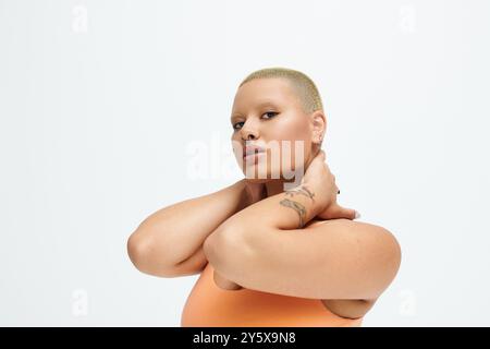 Eine junge Frau mit einem rasierten Kopf posiert mit Anmut und feiert ihre lebhafte Mode-Wahl. Stockfoto