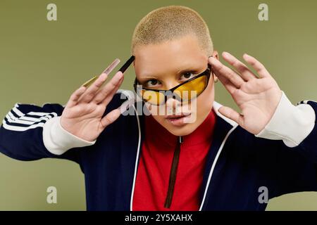 Eine junge kahlköpfige Frau zeigt ihren einzigartigen Stil mit leuchtenden Farben und auffälligen Accessoires. Stockfoto