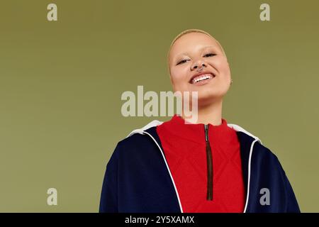 Eine fröhliche junge kahlköpfige Frau strahlt Vertrauen in ihr buntes Outfit aus und lächelt wunderschön. Stockfoto