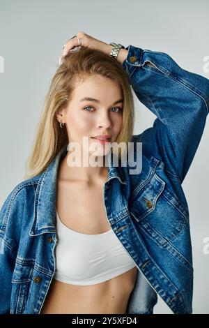 Eine junge Frau zeigt mit fließenden Haaren und einer Jeansjacke ihren lebendigen Sinn für Mode. Stockfoto