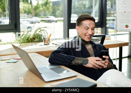 Ein junger Profi teilt einen unbeschwerten Moment am Schreibtisch und lächelt an seinem Telefon. Stockfoto