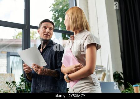 Zwei junge Fachkräfte führen ein Gespräch, während sie im Büro Dokumente prüfen. Stockfoto