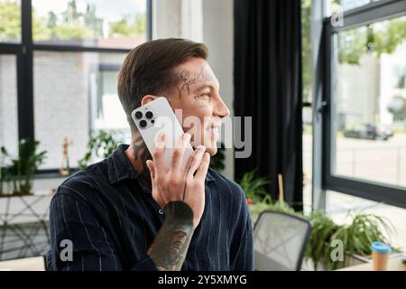 Ein junger Profi spricht am Telefon und lächelt in einem hellen, modernen Bürobereich. Stockfoto