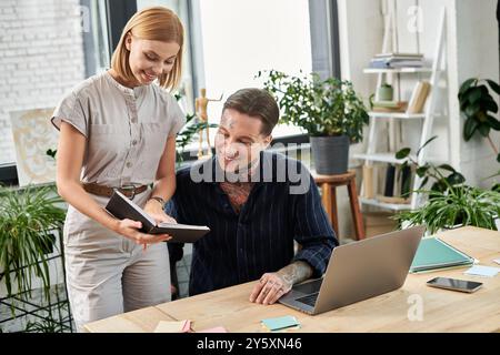 Zwei Kollegen führen ein lebhaftes Gespräch, während sie sich Notizen an einem hölzernen Schreibtisch ansehen. Stockfoto